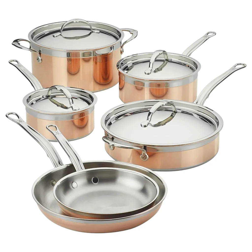 Juego de utensilios de cocina de cobre puro Hestan CopperBond de 10 piezas sobre fondo blanco, que incluye ollas de varios tamaños con tapas de acero inoxidable y dos sartenes apiladas en primer plano.