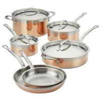 Juego de utensilios de cocina de cobre puro Hestan CopperBond de 10 piezas sobre fondo blanco, que incluye ollas de varios tamaños con tapas de acero inoxidable y dos sartenes apiladas en primer plano.