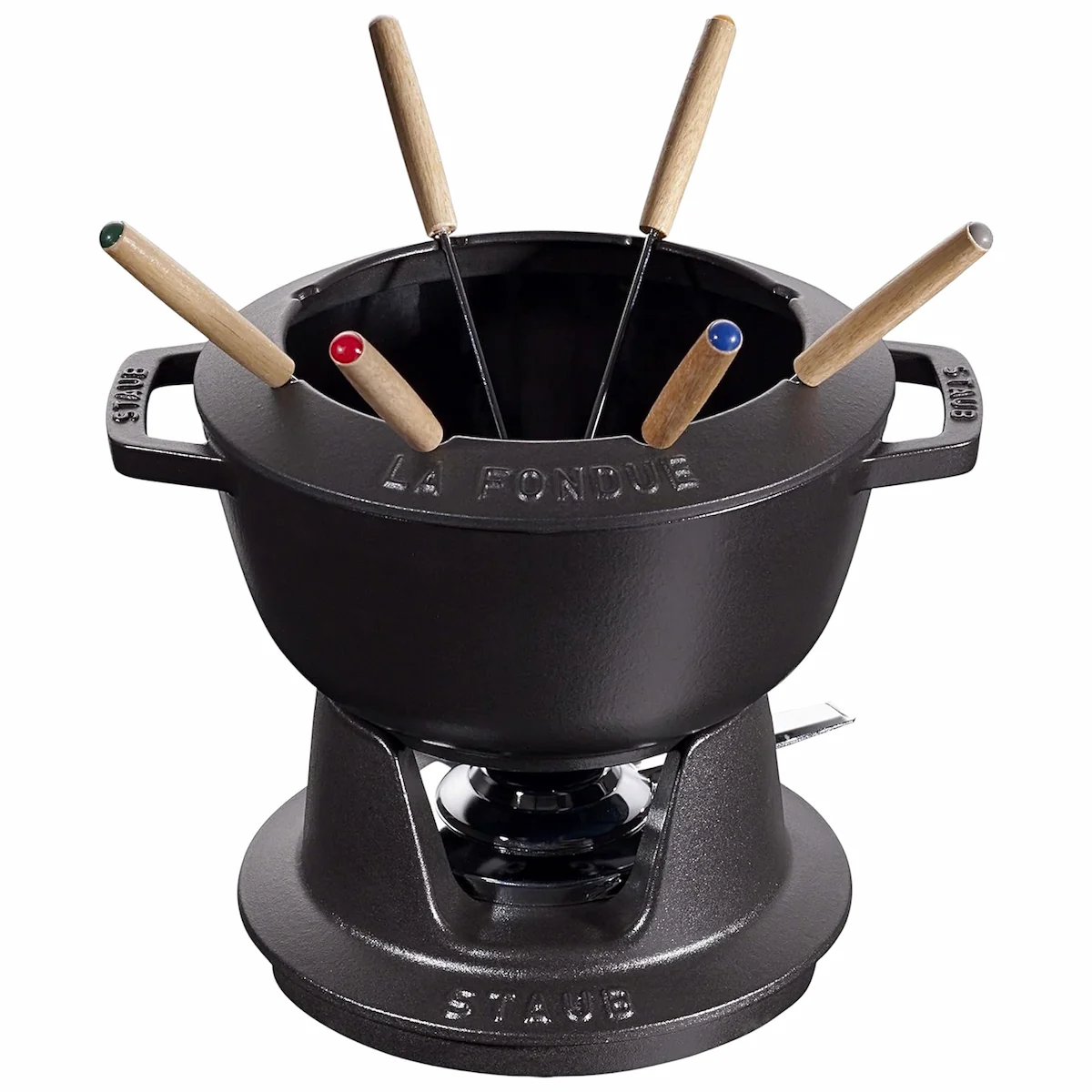 Juego de fondue de hierro fundido negro Staub de 20 cm con base de rechaud, quemador y seis tenedores sobre fondo blanco.