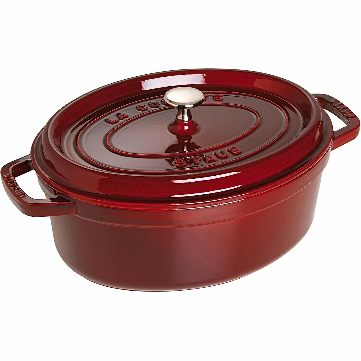 Cacerola Cocotte ovalada de hierro fundido Staub de 29 cm en color rojo granadina (Grenadine) con tapa cerrada y pomo metálico, fotografiada sobre fondo blanco.
