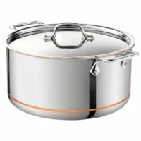 Olla stockpot All-Clad Copper Core de 8 cuartos en acero inoxidable con tapa plana y detalle de franja de cobre visible cerca de la base sobre fondo blanco.